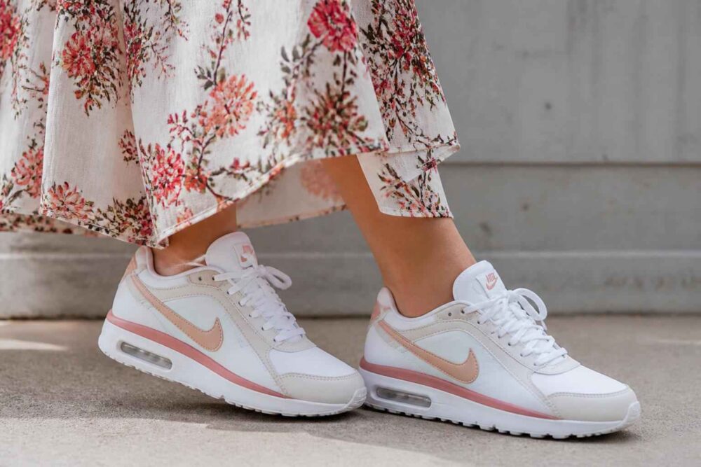 Białe sneakersy Nike z różowymi akcentami pod kwiecistą sukienką